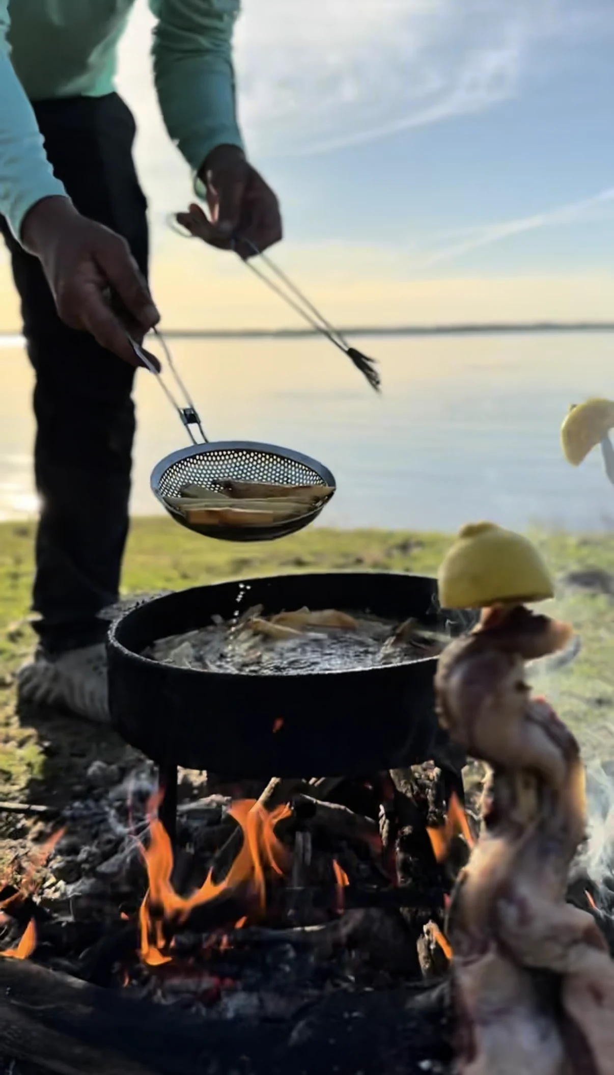 Preparación del almuerzo al fuego junto al río durante una jornada de pesca en Villa Urquiza