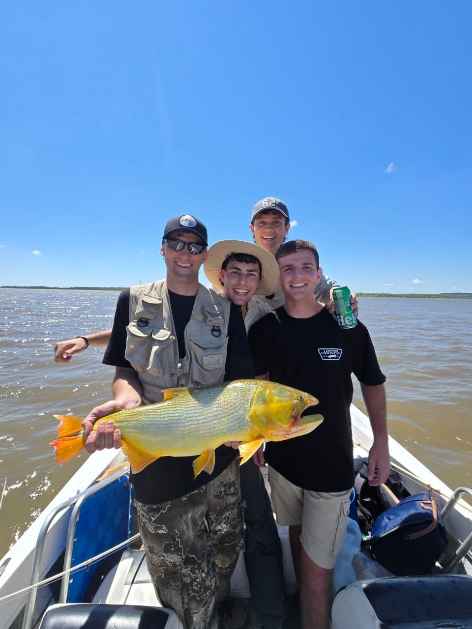 Cuatro pescadores sosteniendo un dorado durante una jornada de pesca en Villa Urquiza, Entre Ríos